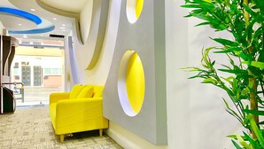 A modern lobby with a yellow sofa, a large mirror, and a potted plant. - Queen Stay Apartments (Sheffield)