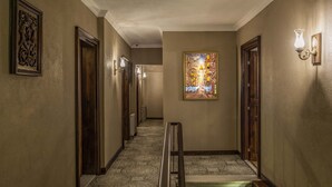 Un couloir avec un tapis à motifs, un escalier doté d’une main courante et une œuvre d’art encadrée accrochée au mur.