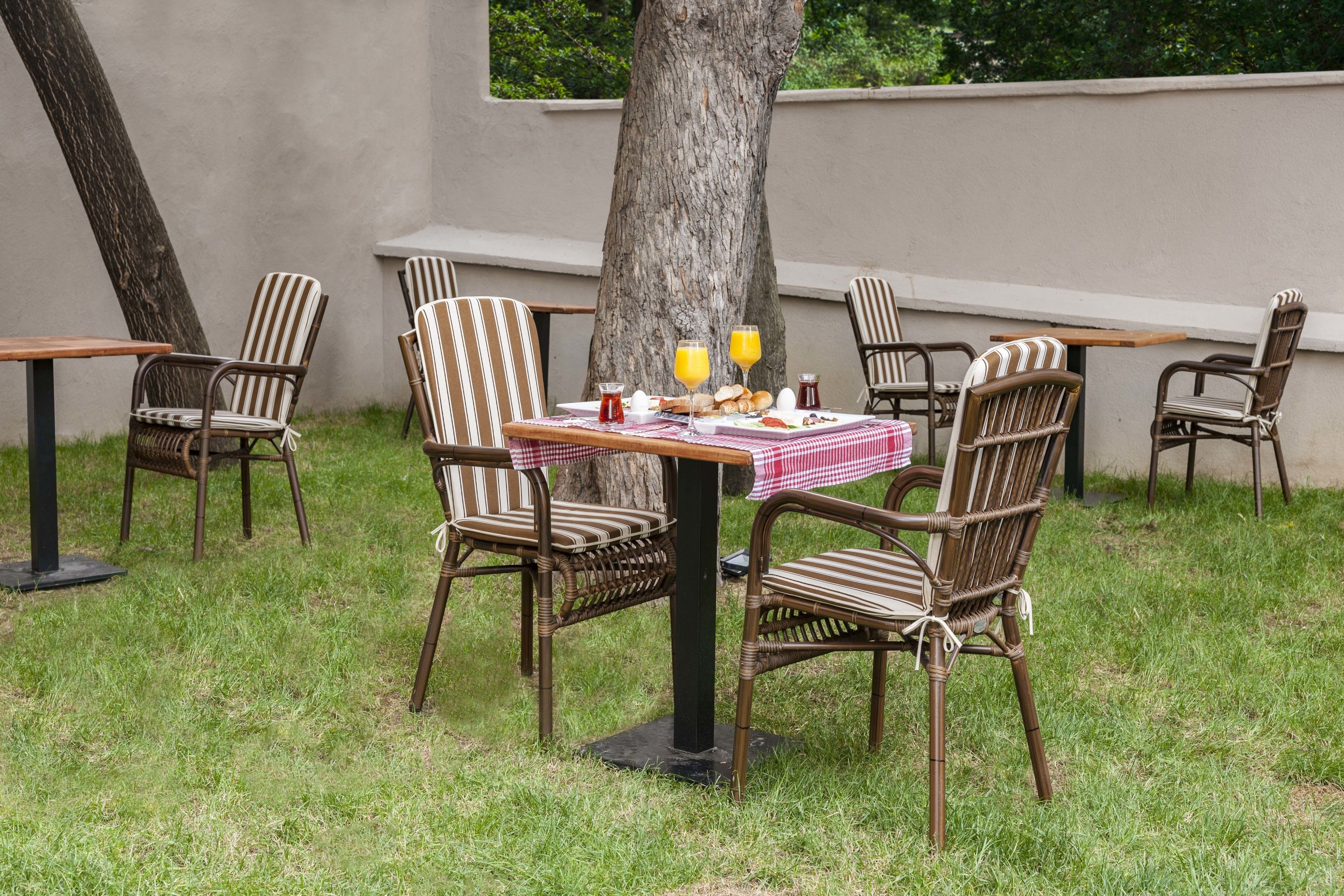 Un área de comedor al aire libre con sillas de mimbre y una mesa preparada para el desayuno.