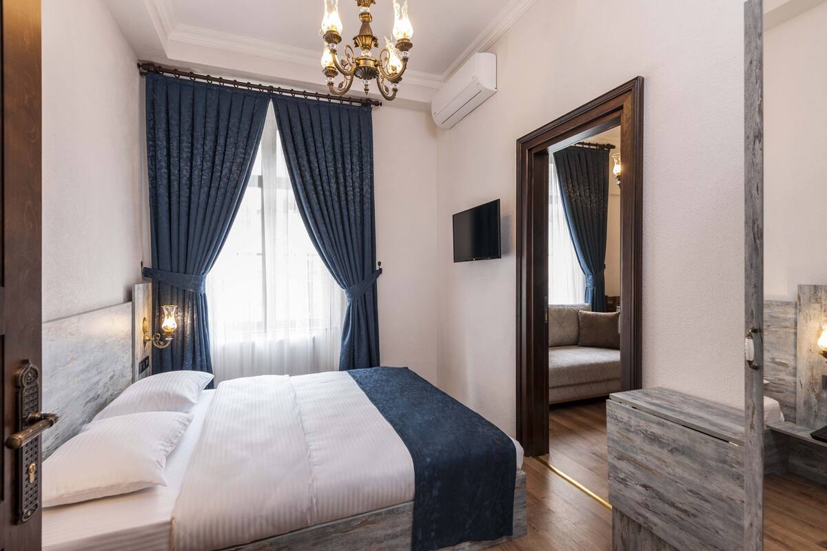 A hotel room with a bed, a TV, a wooden dresser, and a mirror.