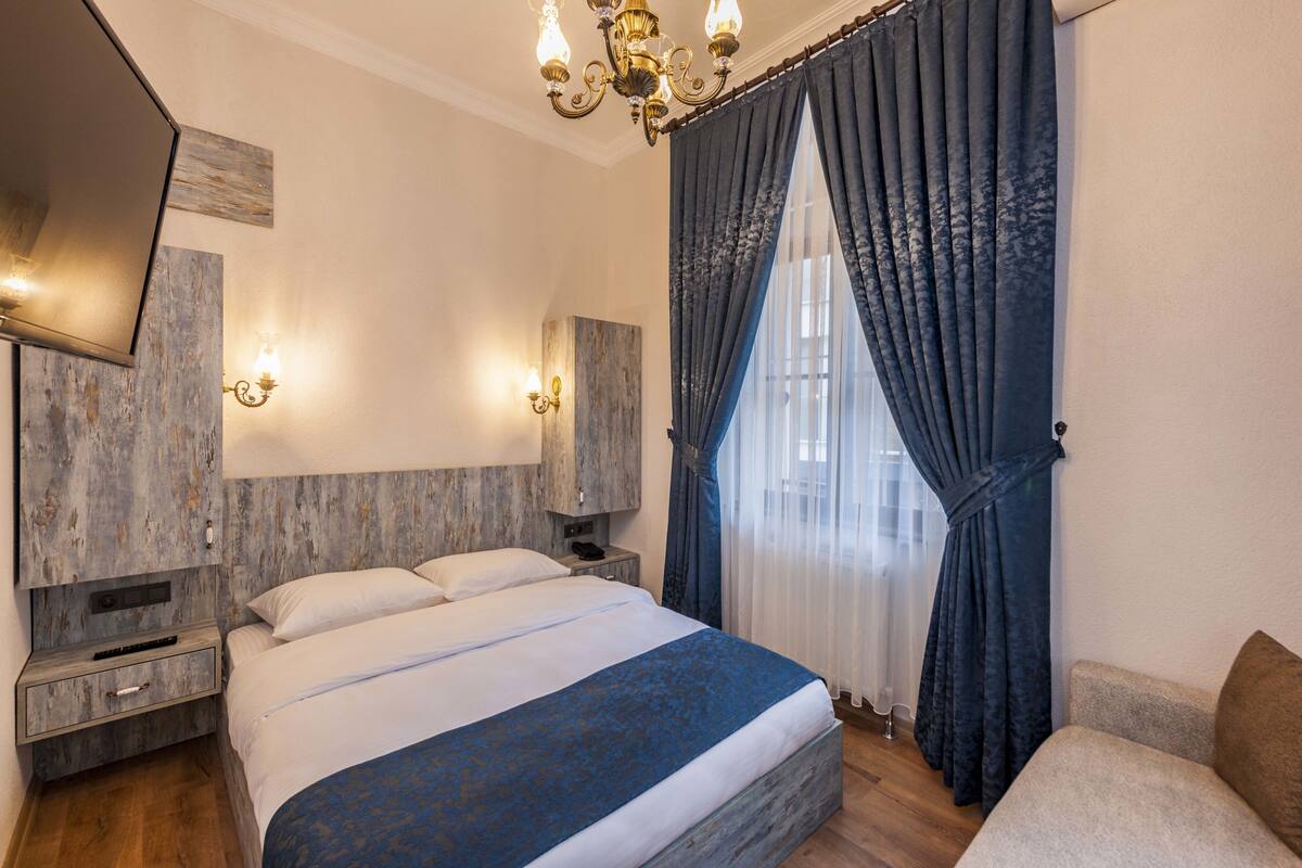 A bedroom with a large bed, a nightstand, a dresser, a chair, and a chandelier.