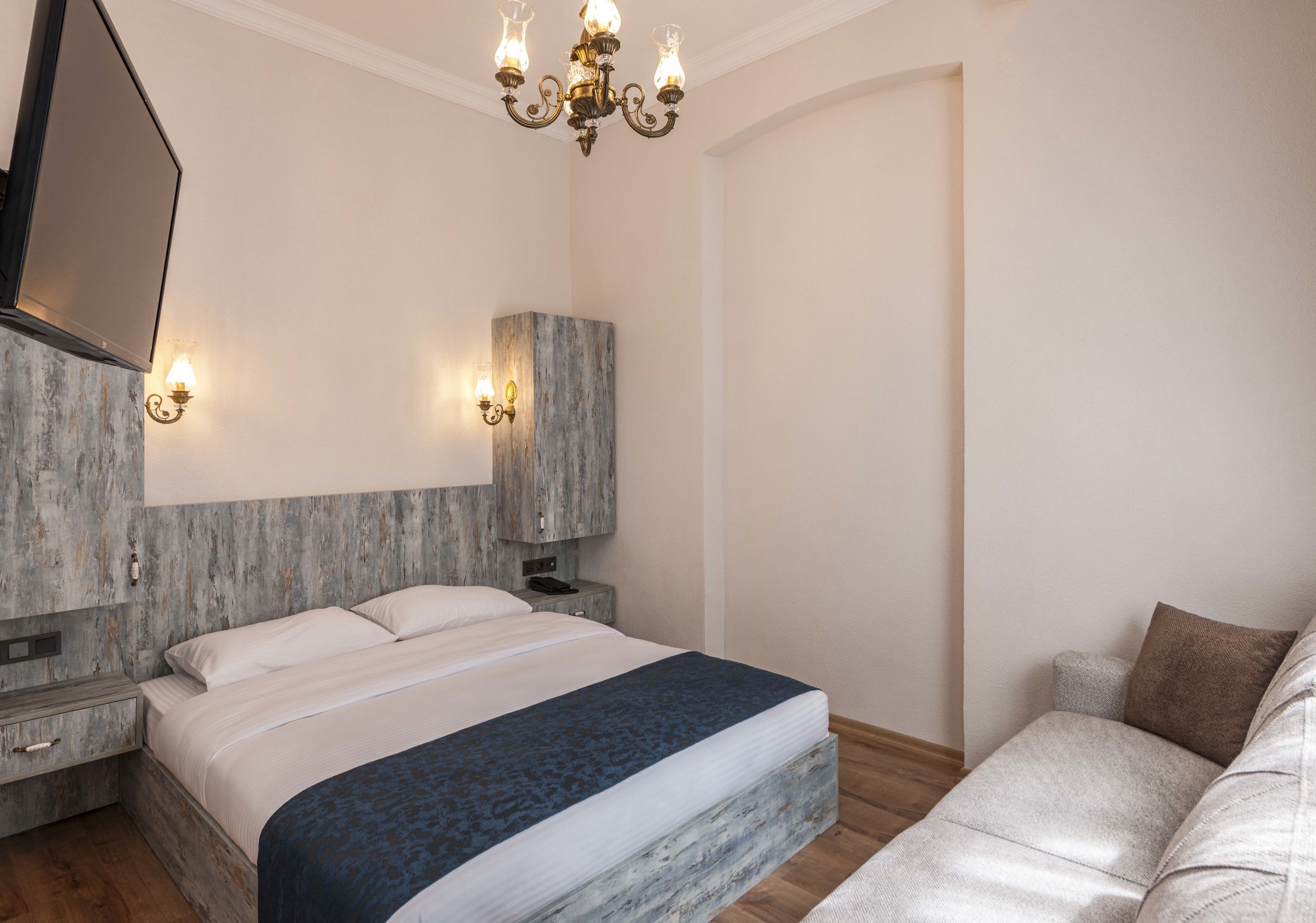 Ein modernes Schlafzimmer mit einem großen Bett, Nachttischen, einem Einbauschrank und einer Chandelüster.