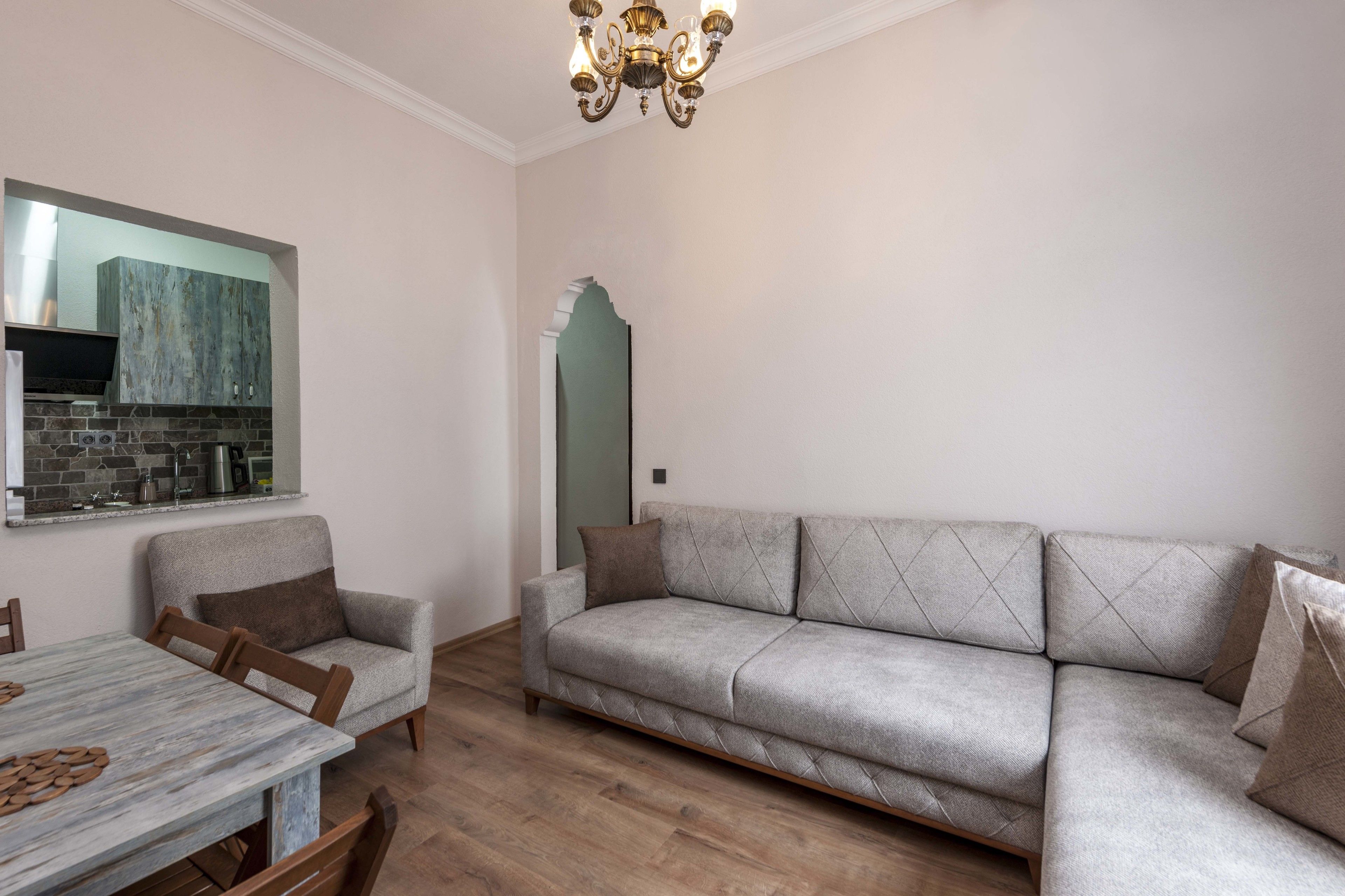 A living room with a sofa, armchairs, a dining table, and a kitchen area with a built-in stove.