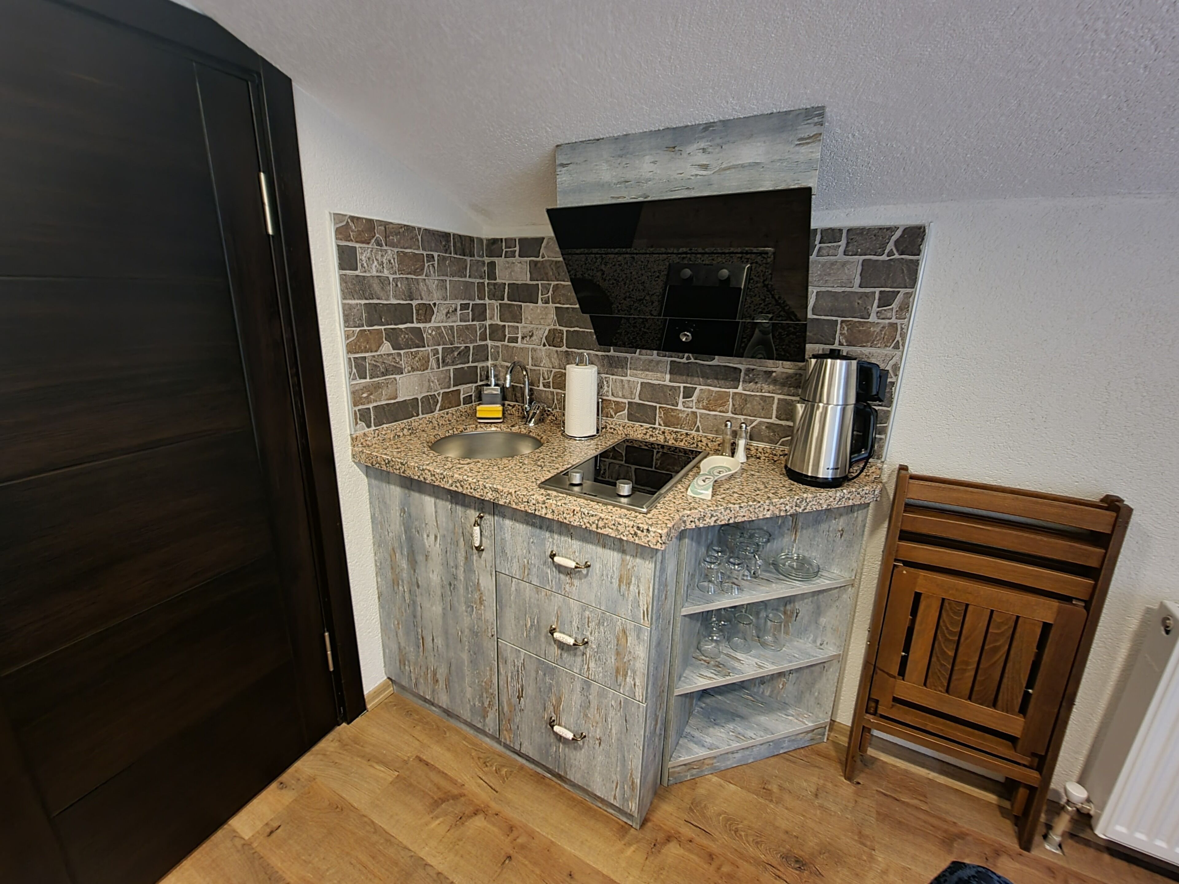 A compact kitchen with a granite countertop, a built-in stove, and a coffee maker.