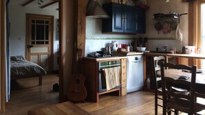 A cozy kitchen with wooden beams, a dining table, and a guitar.