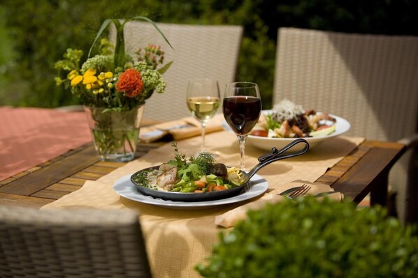 A table set outdoors with a meal, a glass of white wine, and a glass of red wine. - Hotel Eisbach (Ransbach-Baumbach)