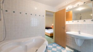 A modern bathroom with a bathtub, a sink, and a shower. - Hotel Eisbach (Ransbach-Baumbach)