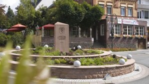A historic building with a prominent tower, a landscaped garden with a circular fountain, and a restaurant with outdoor seating. - Hotel Eisbach (Ransbach-Baumbach)