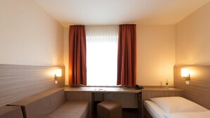 A hotel room with two single beds, a small desk with a chair, and a window with curtains. - Hotel Eisbach (Ransbach-Baumbach)