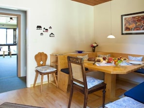 A cozy dining area with a wooden table and chairs, a bench, and a wall decorated with small house cutouts. - Cafe Alt Willingen (Willingen)