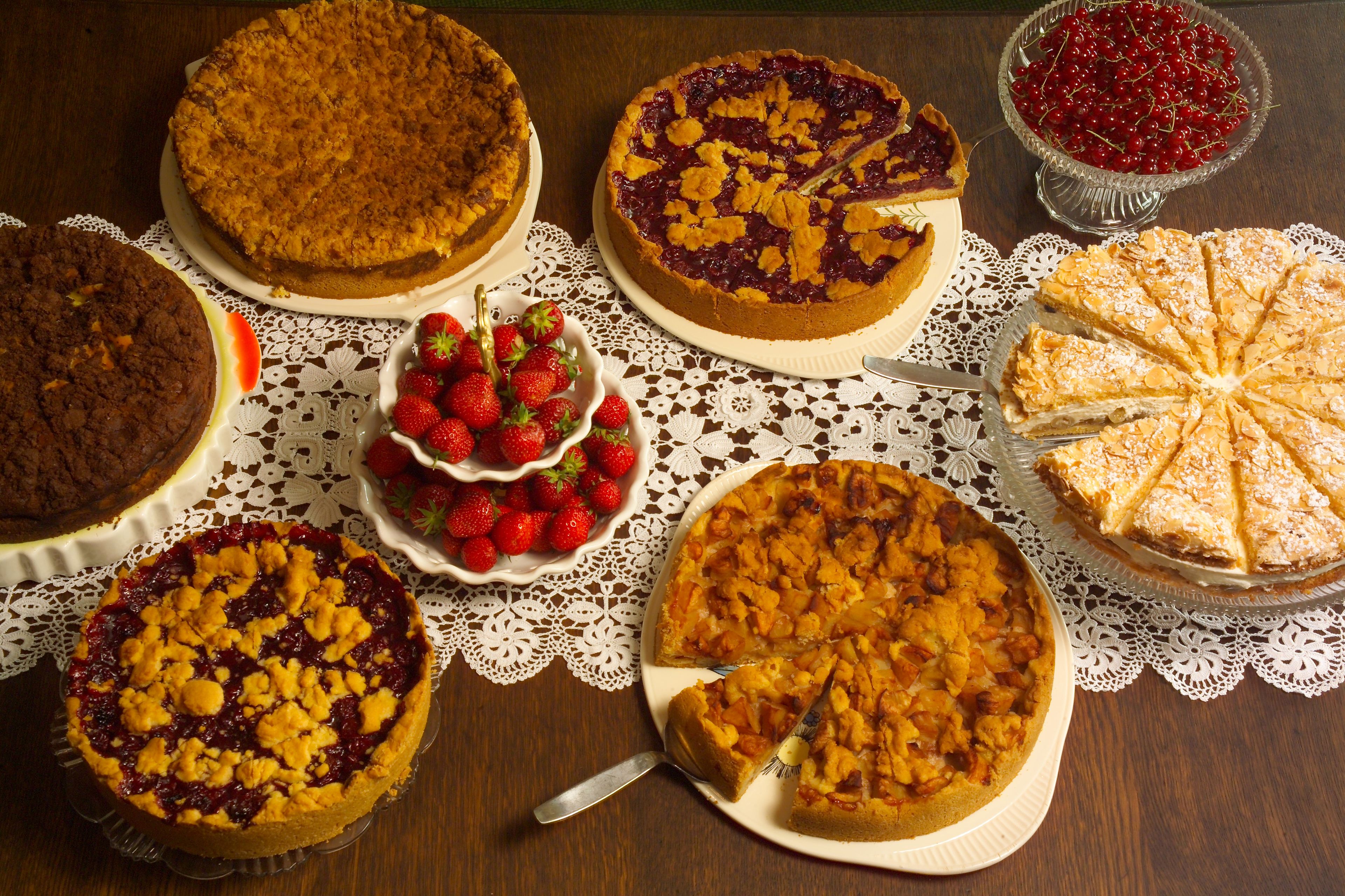 A variety of pies on a wooden table with a lace tablecloth.