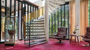 A modern interior with a red carpet, a staircase with black railings, and two leather chairs. - Hotel Hammersø Apartments - Adults Only (Allinge)