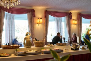 Zona pranzo con angolo buffet, ampie finestre con tende e illuminazione a parete.