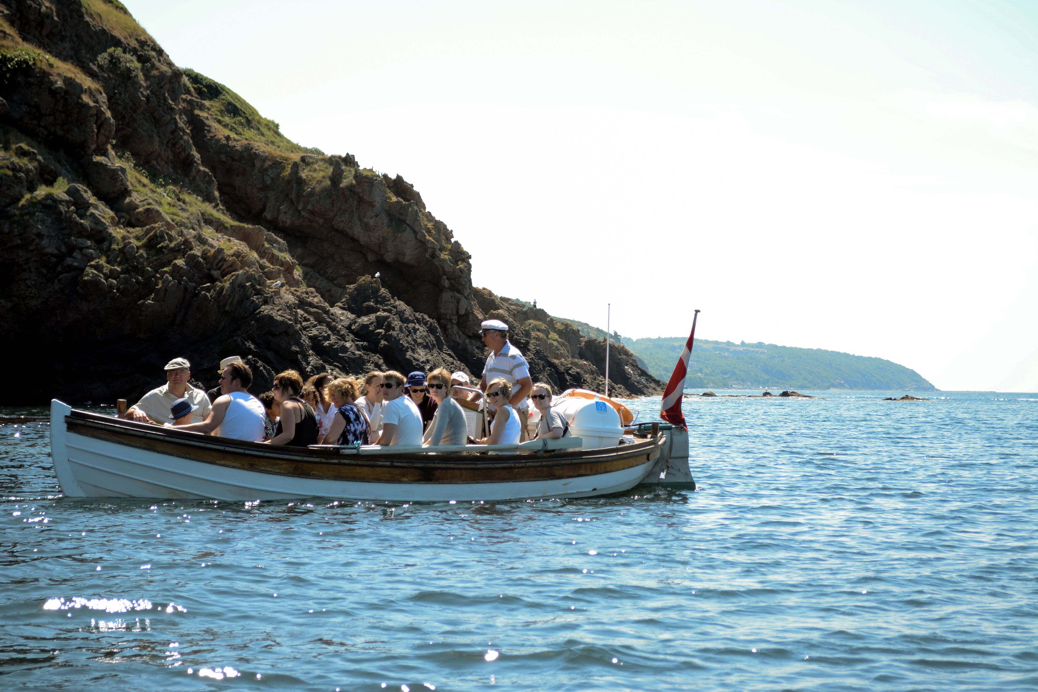 Un bateau transportant des passagers longe une côte rocheuse.