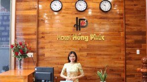 A reception desk with clocks, a sign reading "Hotel Hương Phước," and a receptionist. - Hotel Hong Phuc (Quy Nhon Nam)