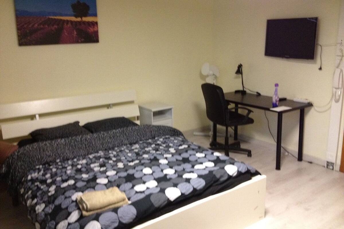 Een slaapkamer met een bed, een bureau en een stoel.