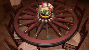 Una mesa redonda de madera con un arreglo floral en el centro, rodeada de sillas.
