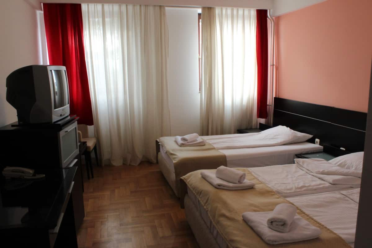 A hotel room with two beds, a TV, and a desk.