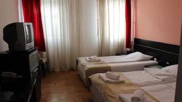 A hotel room with two beds, a TV, and a desk.