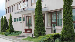 A hotel with a signboard, a covered entrance, and tall, narrow trees in front. - Hotel Yu (East Sarajevo)