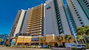 A multi-story hotel with a prominent sign for "The Peninsula" on the facade. - Pet Friendly, Direct Oceanfront, True One Bedroom (Myrtle Beach)