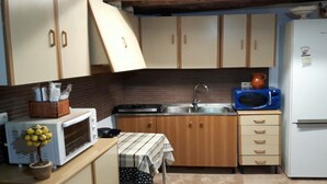 Une cuisine de taille réduite, dotée de meubles de rangement en bois, d’un four à micro-ondes, d’un évier et d’un réfrigérateur.
