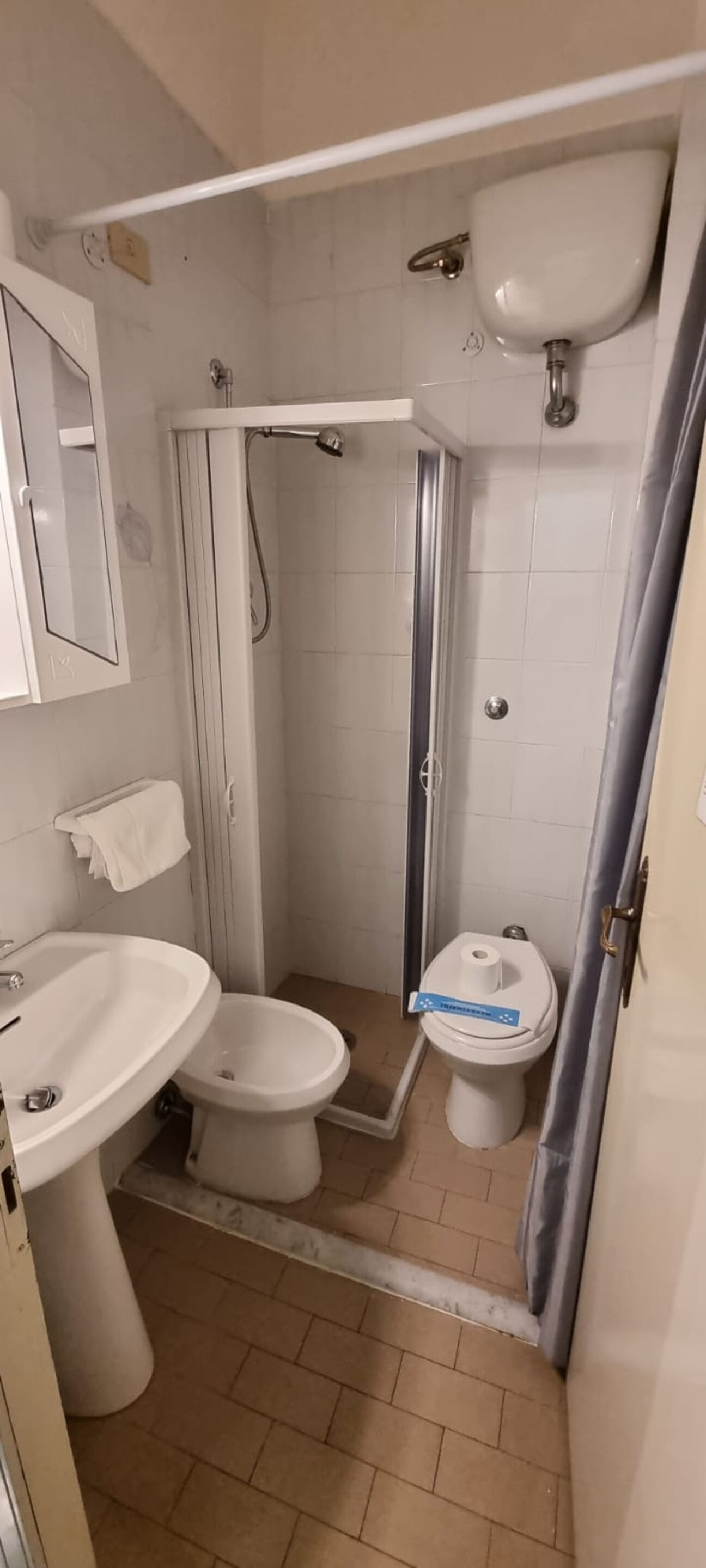 Un bagno piccolo con doccia, due servizi igienici, un lavandino e uno specchio.