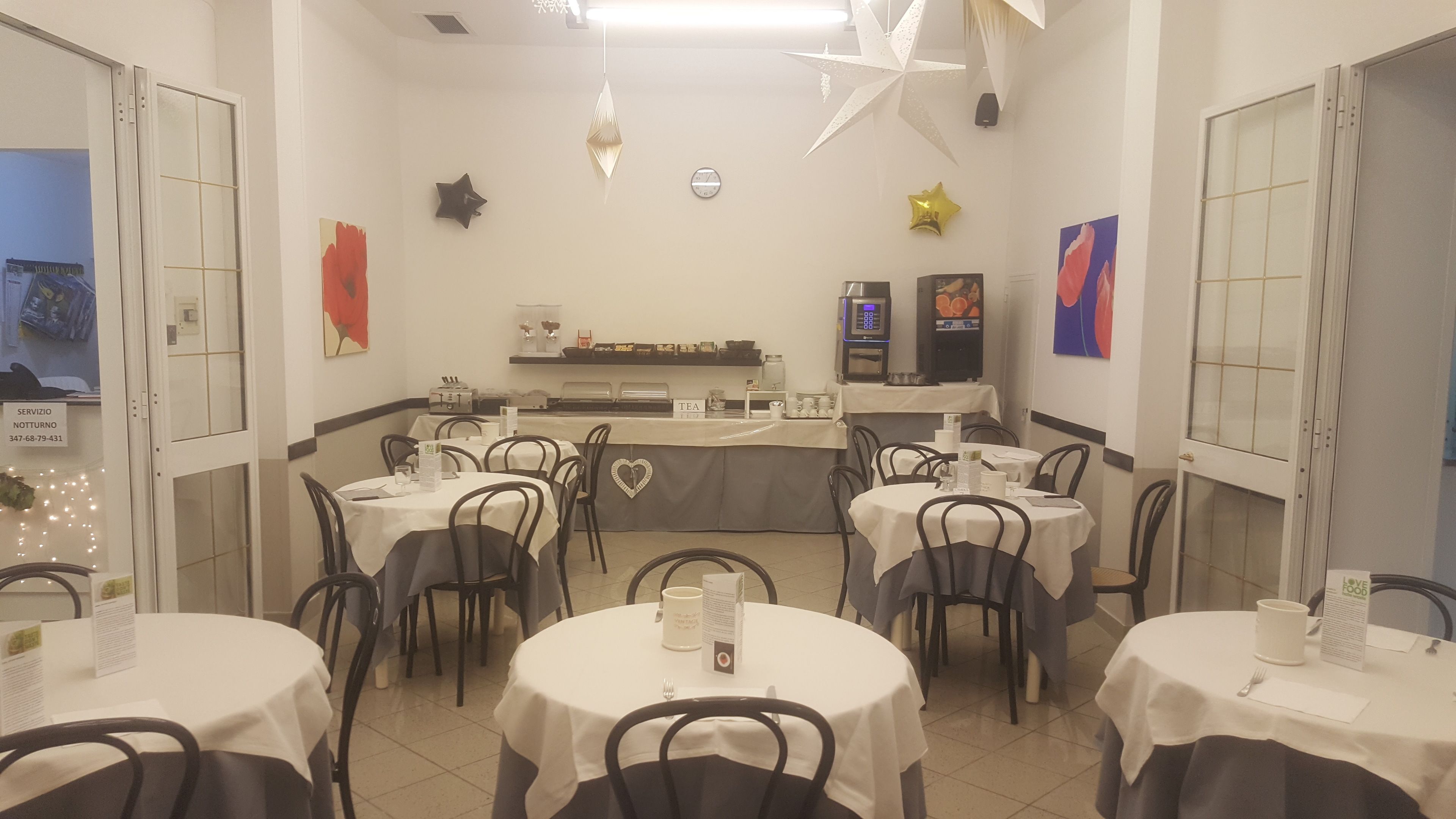 A restaurant with round tables, chairs, a counter with a tea station, and decorative elements like stars and a clock on the wall.