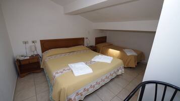 A hotel room with a large bed, a smaller bed, a chair, and a nightstand with a lamp.