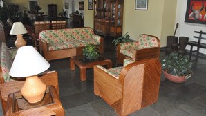 A traditional living room with wicker furniture, a wooden cabinet, and a dining area in the background. - Hotel Termópolis (Sao Sebastiao do Paraiso)