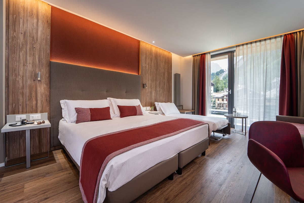 Une chambre d’hôtel moderne, dotée d’un grand lit, d’un bureau et offrant une vue sur les montagnes.