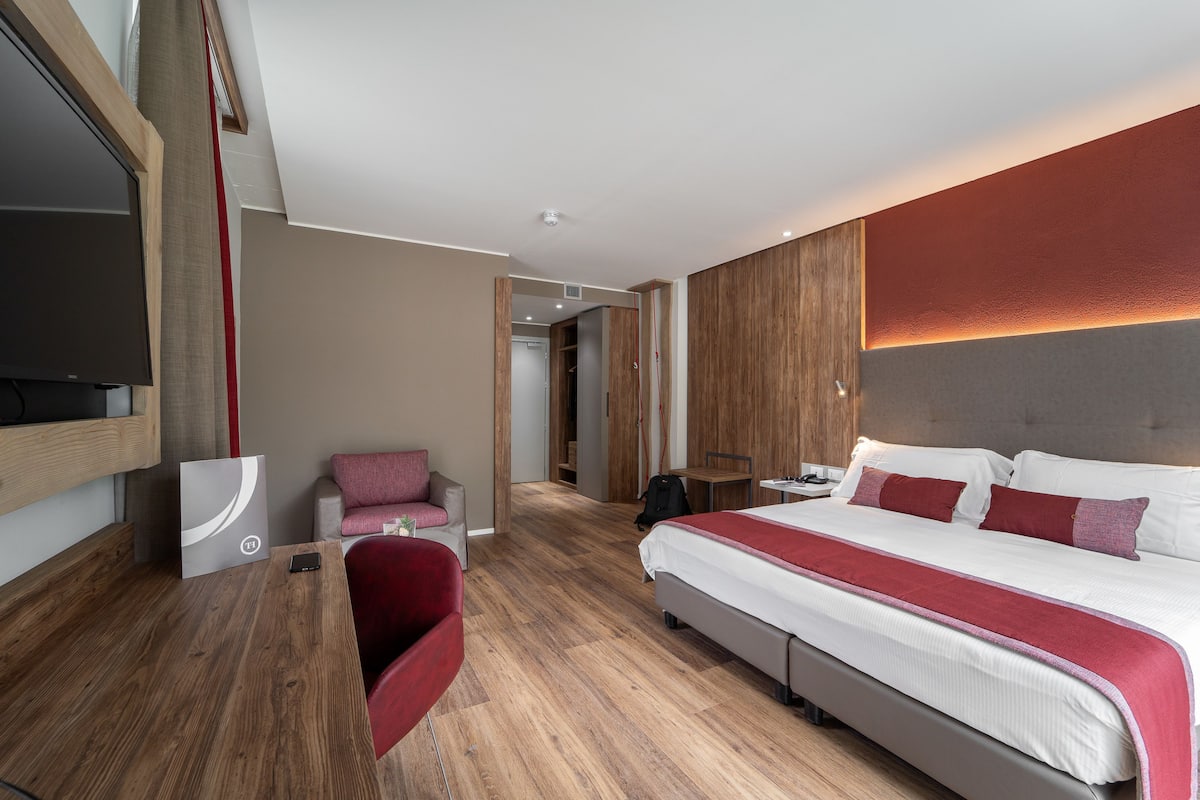 Une chambre d’hôtel moderne équipée d’un grand lit, d’un bureau et d’une télévision.