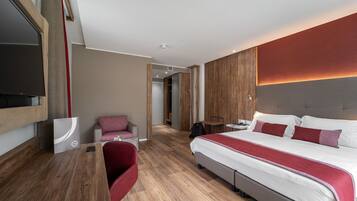 Un habitació d'hotel moderna amb un llit gran, una taula de treball i una televisió.