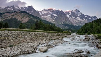 A river flowing through a rocky landscape with a stone wall on one side and a mountain range in the background.