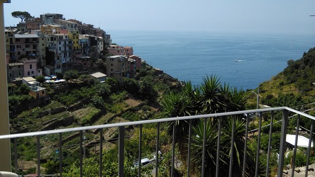 Un pueblo costero con edificios coloridos, una vista despejada del mar y un balcón con barandilla.