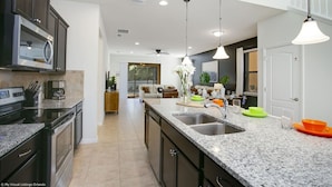 A modern kitchen with granite countertops, stainless steel appliances, and pendant lighting.