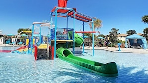 A water park with a central play structure, slides, and a pool.