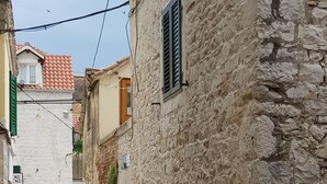 Una calle estrecha con edificios de piedra, una puerta visible y un cartel.