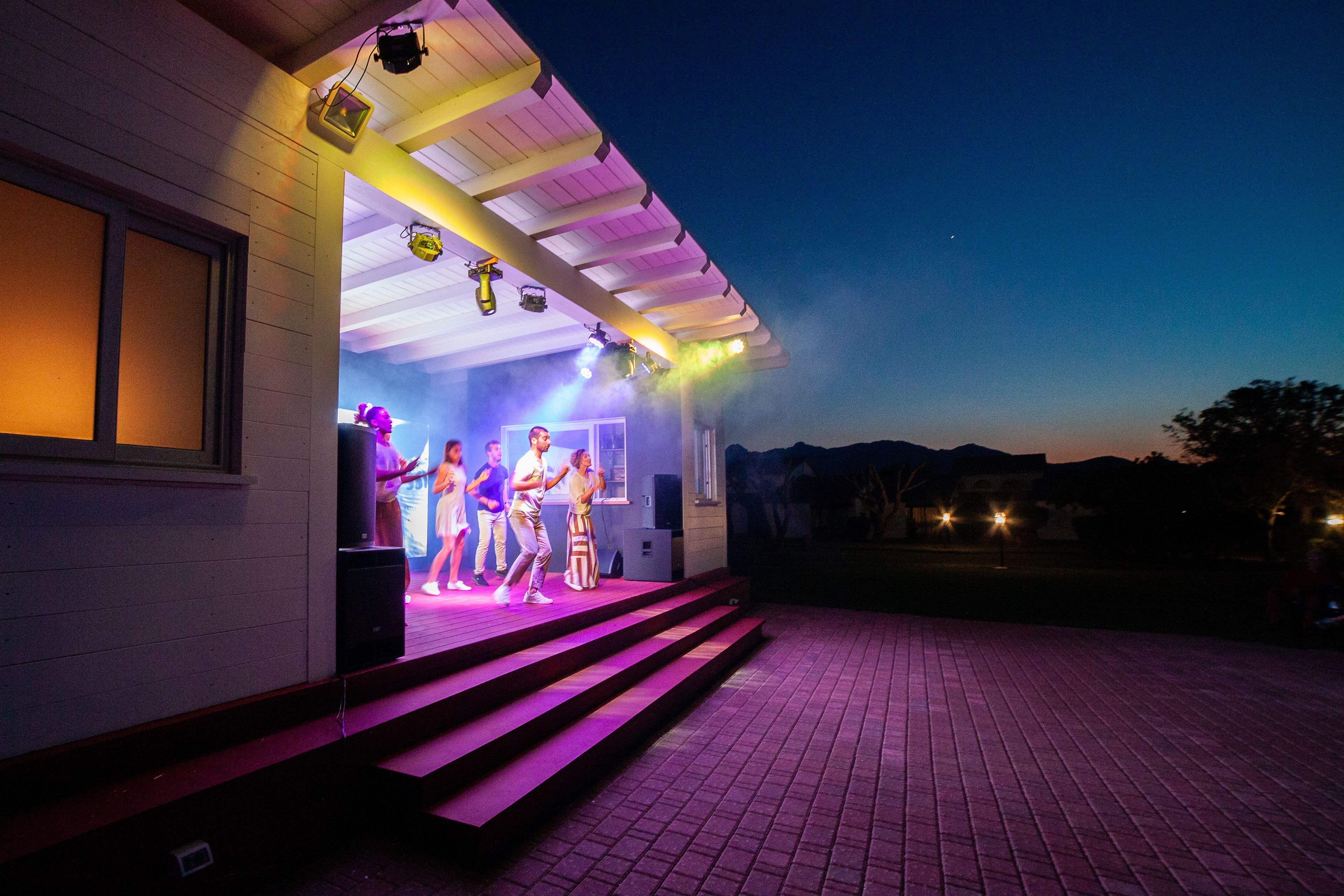 A stage with steps leading up to it, a building with a white exterior, and a clear sky.