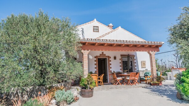 A house with a patio, outdoor furniture, and potted plants.