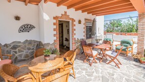 A covered patio with stone walls, wicker furniture, and a brick archway.