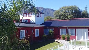 Un bâtiment rouge doté d’une piscine, entouré de verdure et de montagnes.