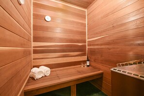 A sauna room with wooden walls, a bench, towels, and a bottle of water.