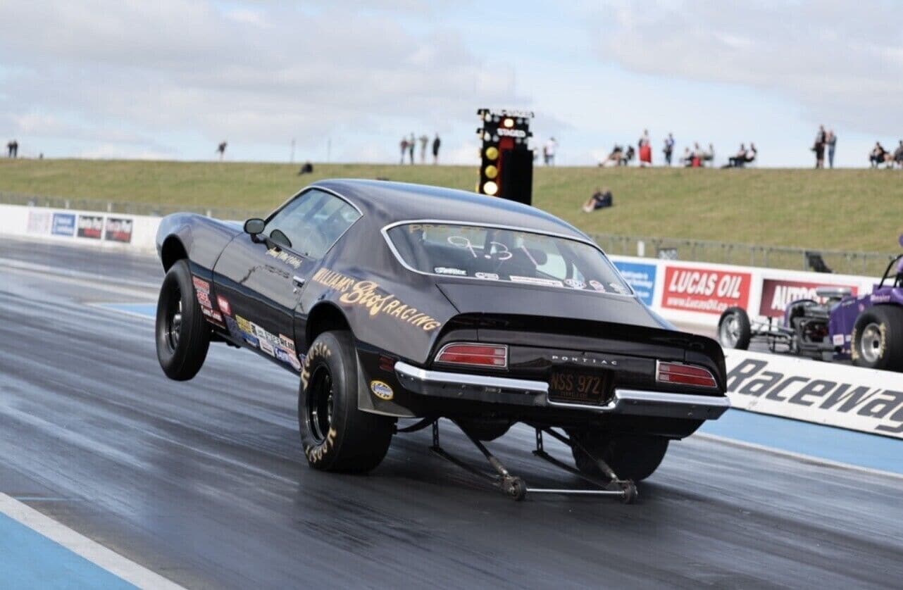 Een oldtimer die een donut doet op een dragstrip.