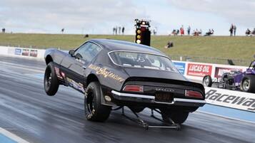 Een oldtimer die een donut doet op een dragstrip.
