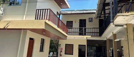 Un edificio de dos pisos con un balcón, un extintor y una puerta.