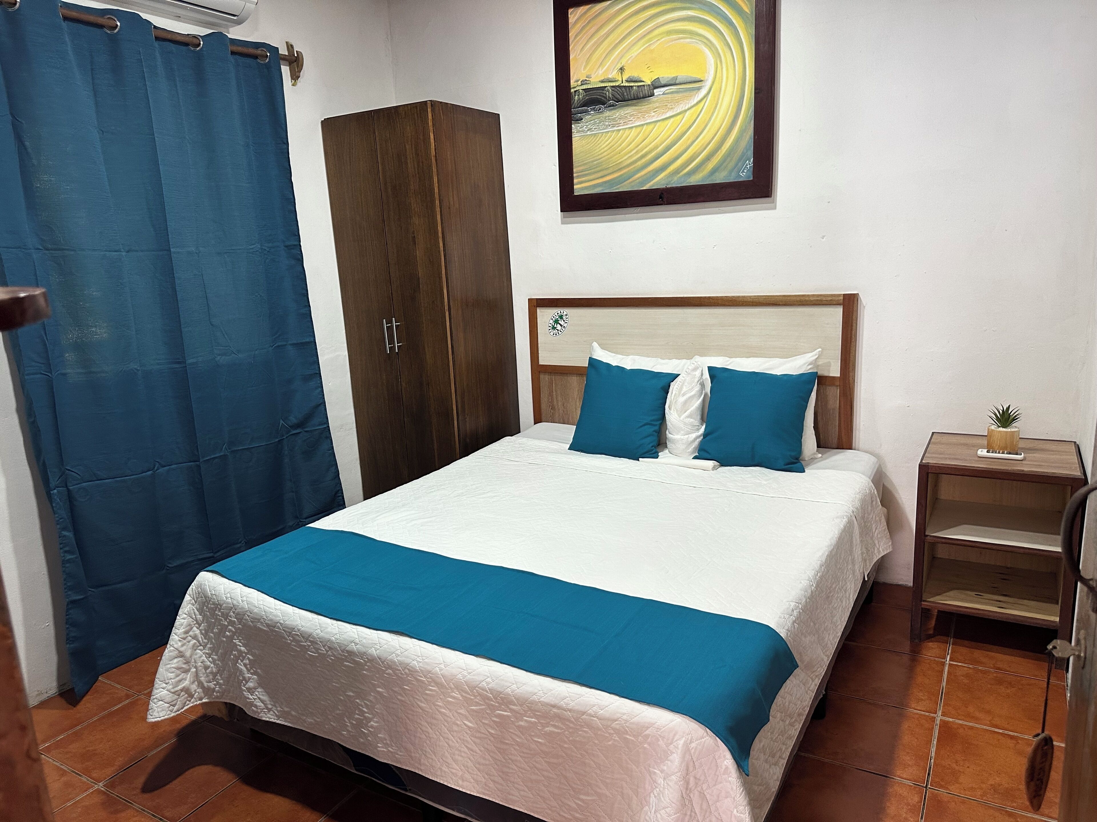 Una camera da letto con un letto, un armadio, un comodino e un quadro appeso al muro.