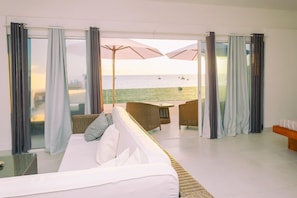 A room with a white sofa, wicker chairs, and a view of the sea. - Etoile Blanche (Nosy Be)