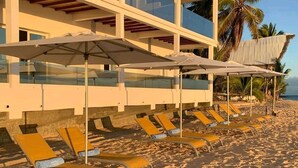 A beachside hotel with sun loungers and umbrellas, a pool area, and a view of the ocean. - Etoile Blanche (Nosy Be)