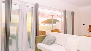 A hotel room with a balcony, white curtains, a wicker sofa, and a view of the sea. - Etoile Blanche (Nosy Be)